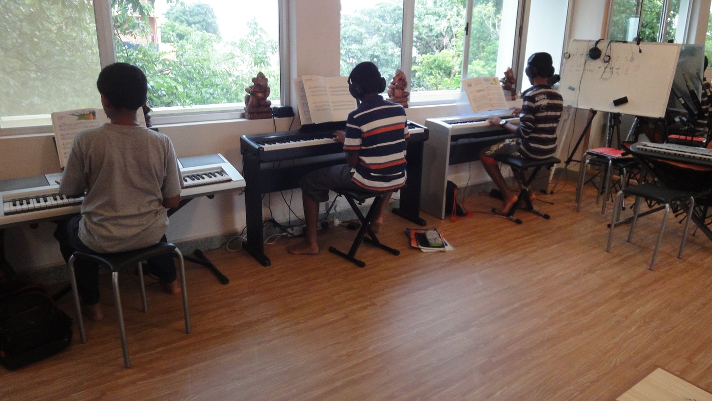 Learners practising at a row of keyboards in a bright classroom.
