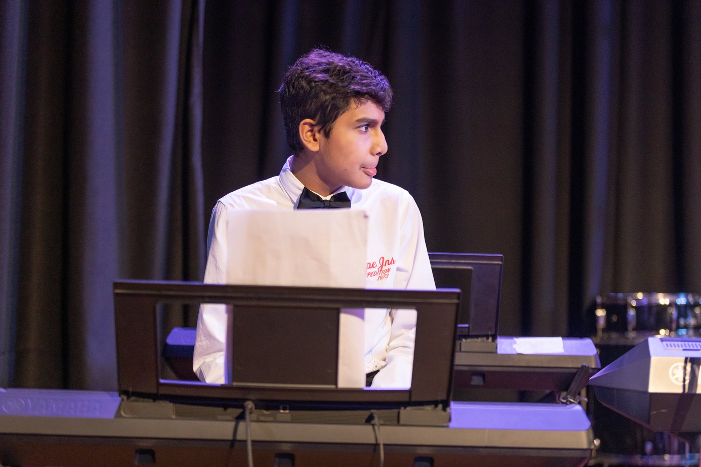 A young keyboard player on stage behind a music stand.